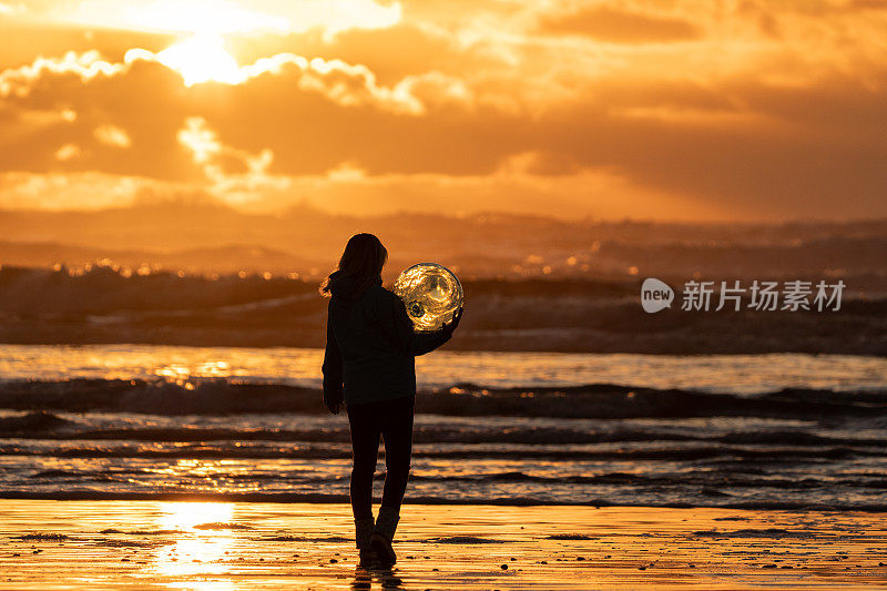 日出时，女人在海滩边拿着水晶球