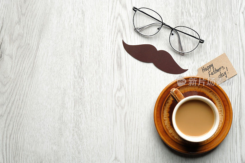 父亲节快乐。父亲节的题词，小胡子，一杯咖啡和男眼镜在木制桌子上顶视图。父亲节横幅模板。