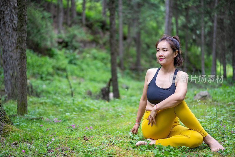 年轻的亚洲女人在森林里练习瑜伽