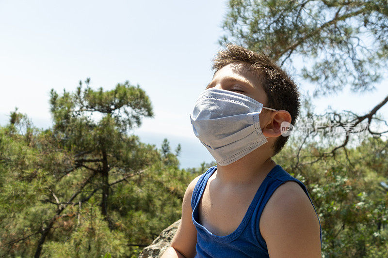 男孩试图用外科口罩呼吸阳光，以避免冠状病毒Covid-19
