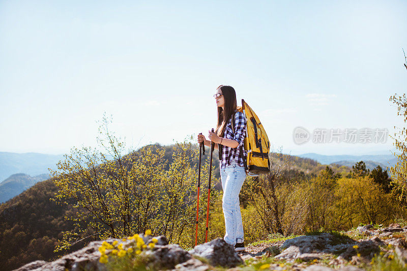 一位年轻的背包客在山顶欣赏风景