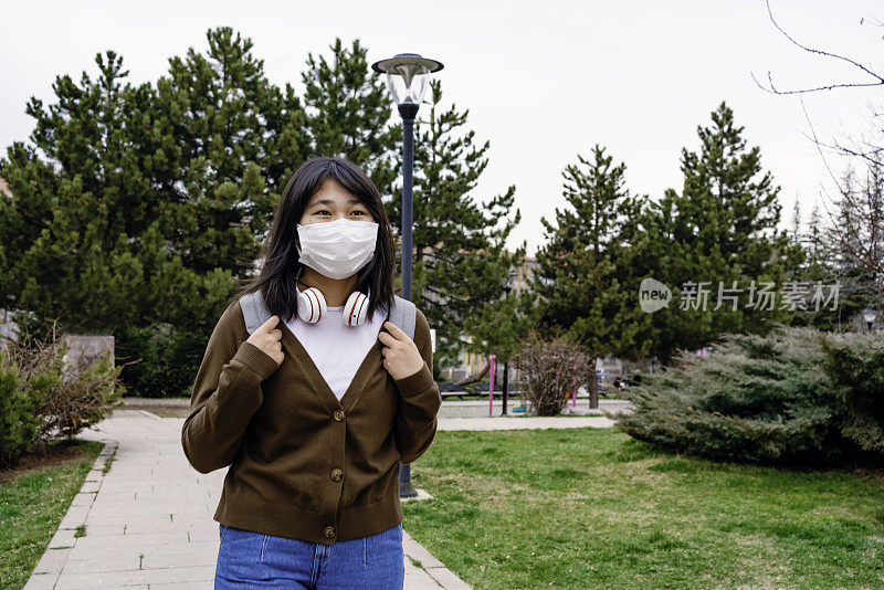 回到学校。日本血统的女孩在校园里。她戴着防护口罩。