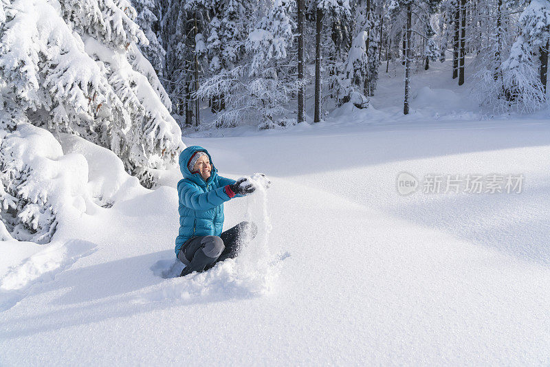 在冬天的森林里，成熟的女人穿着皮大衣向空中抛雪