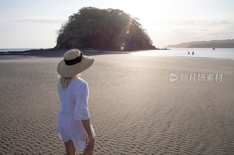 一个女人在清晨退潮时走在海滩上