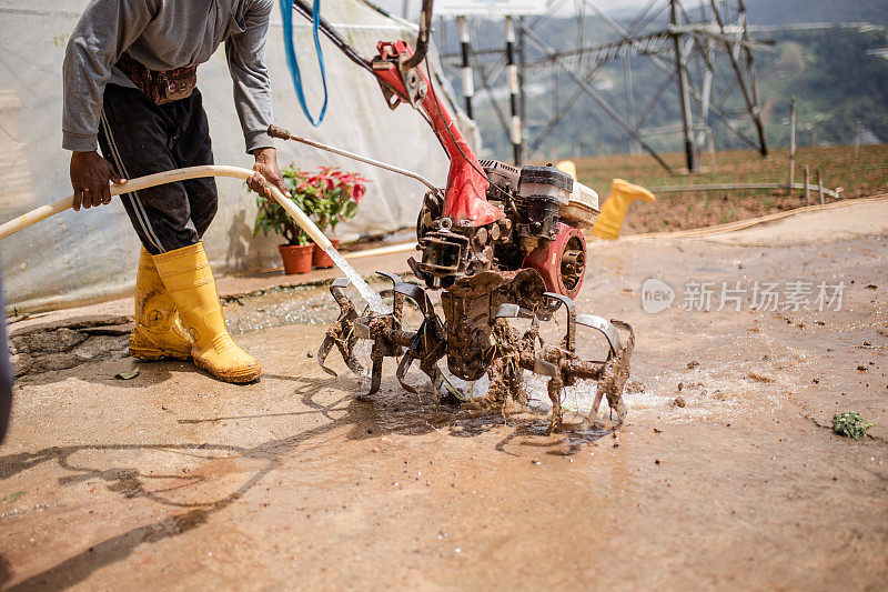 亚洲男性农民用水清洗手摇拖拉机