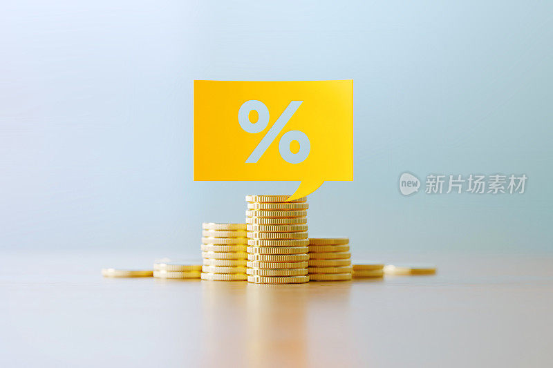 预算和贷款概念-百分比标志写的黄色讲话气泡坐在硬币堆栈前散焦背景