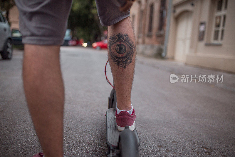 有纹身的中年男子在街上骑电动车
