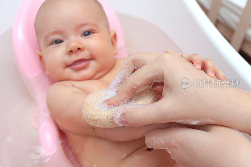 新生儿在浴缸里用海绵和泡沫洗澡