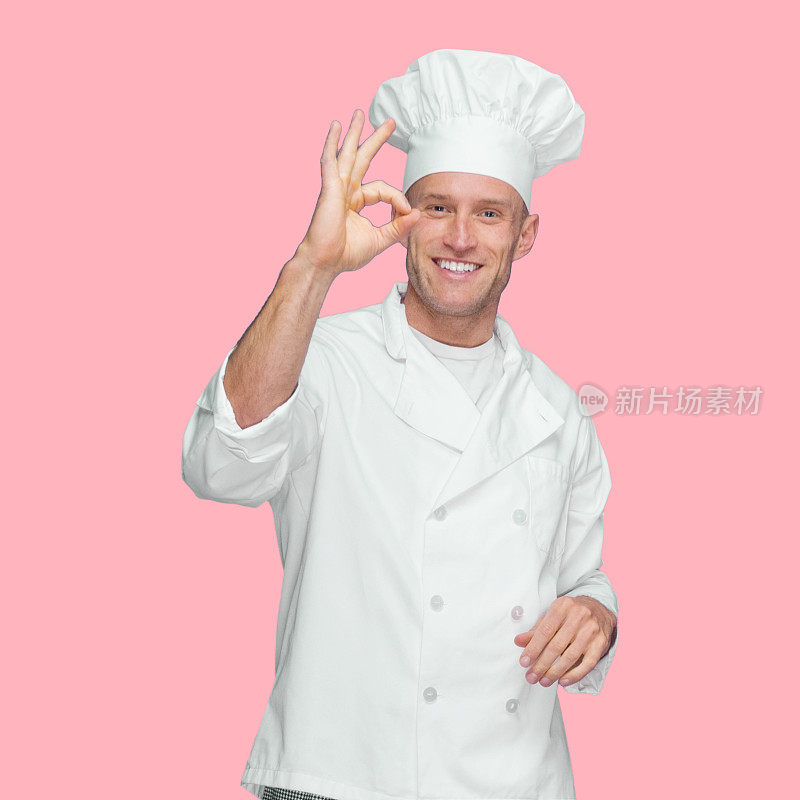 白人男厨师穿着夹克站在有色背景前