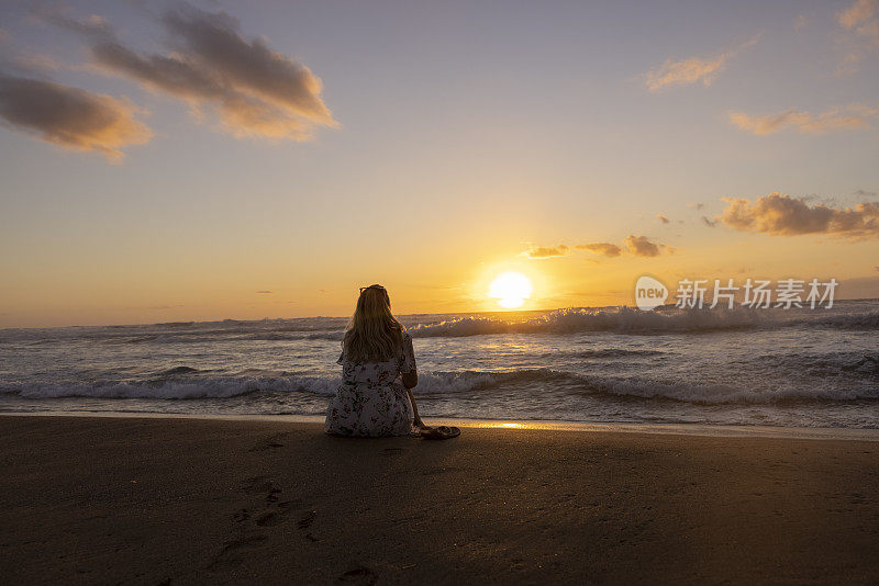 在意大利撒丁岛，在夕阳下的海滩上放松的体贴的女人。