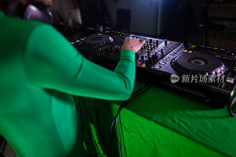 辨认不出的男性DJ，在绿色的屏幕前一边播放音乐一边录制音乐视频