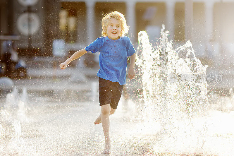 阳光明媚的夏日，一个小男孩在干涸的喷泉喷泉间的广场上玩耍。城市里孩子们的活跃休闲活动。