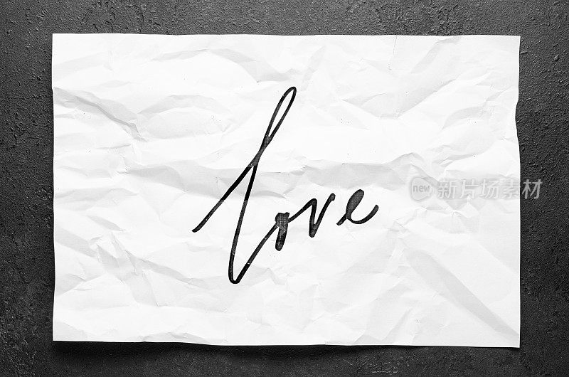 爱。不要放弃。在皱巴巴的白纸上刻字。手写的文本。鼓舞人心的名言。
