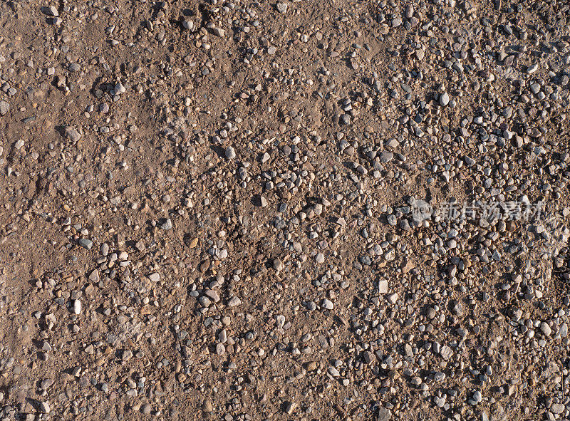 背景，俯视图。乡村道路上的沙子和砾石。金色的沙子和光滑的小鹅卵石铺在路上。概念背景沙子和砾石。