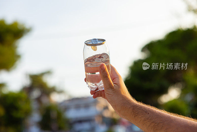 面目全非的男人拿着装着水的塑料罐，以大自然为背景