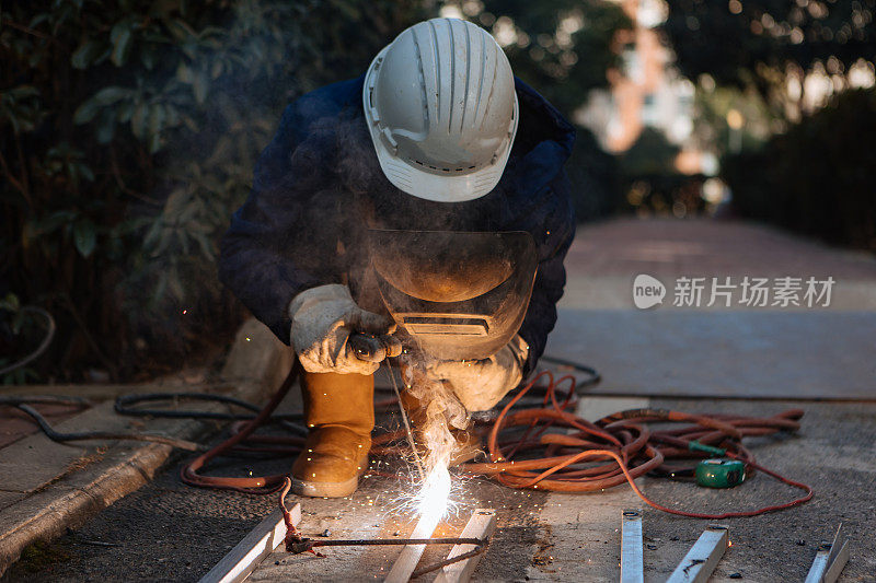 一名中年男性工人正在使用切割机和焊机