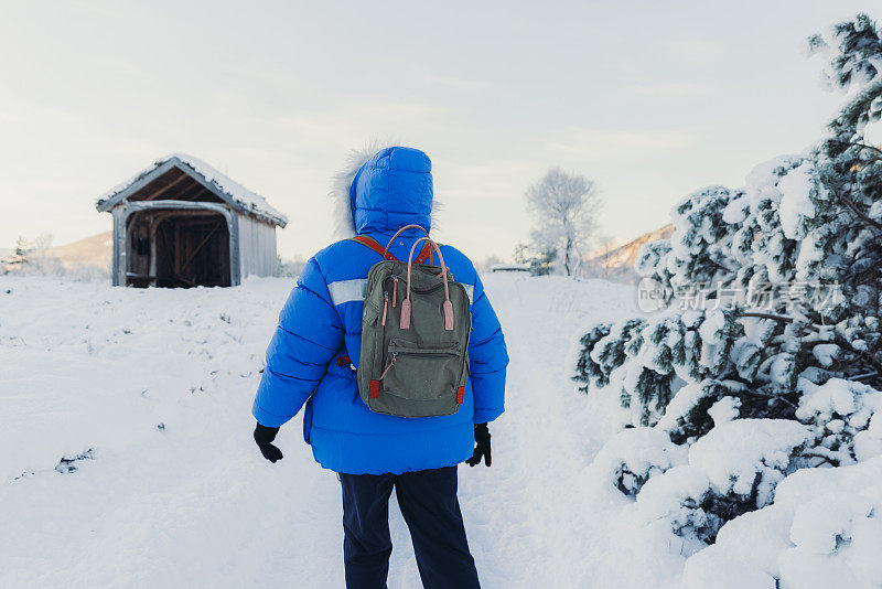 挪威，一名女子背包客在冰天雪地的小路上漫步，前往收容所