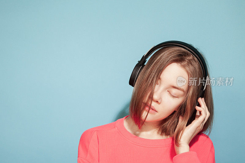 22岁快乐的亚洲女人用无线耳机听音乐