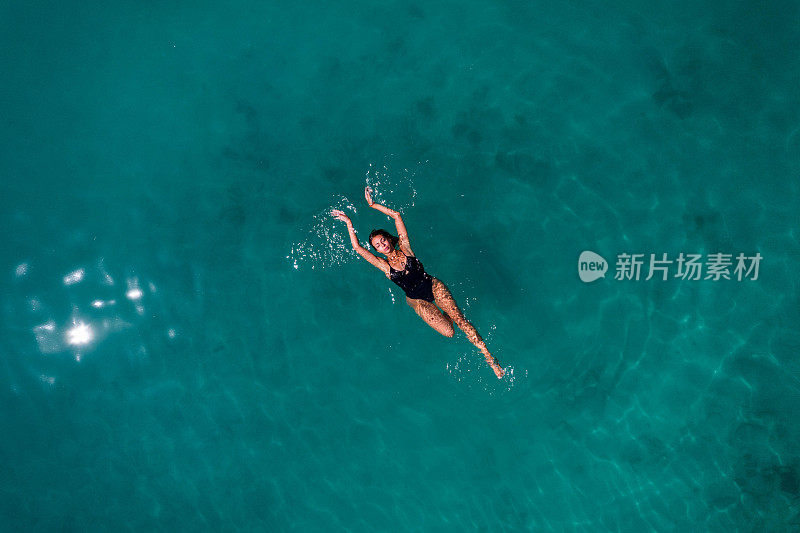 年轻女子漂浮在深蓝色的大海上