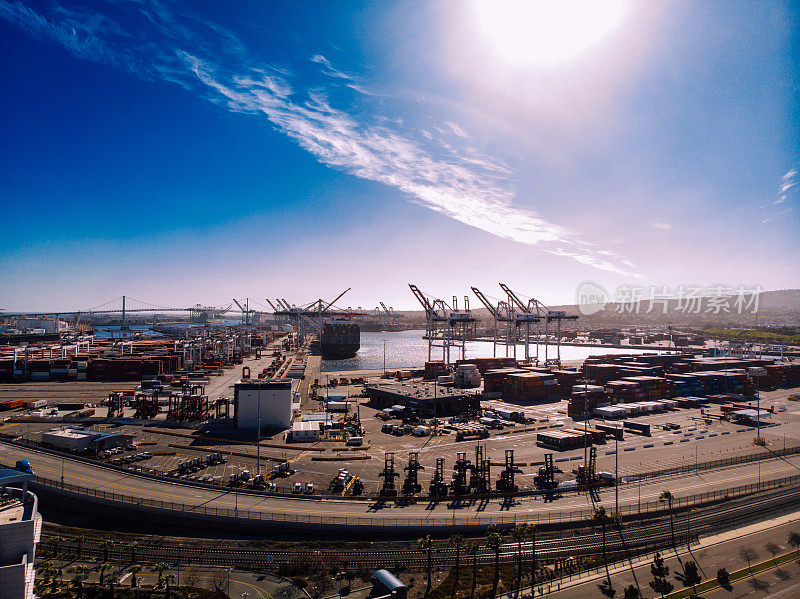 从高空俯瞰，庞大的洛杉矶港口像一个精心组织的迷宫，由起重机、集装箱和货船组成，是一个繁忙的全球贸易和海上活动中心。