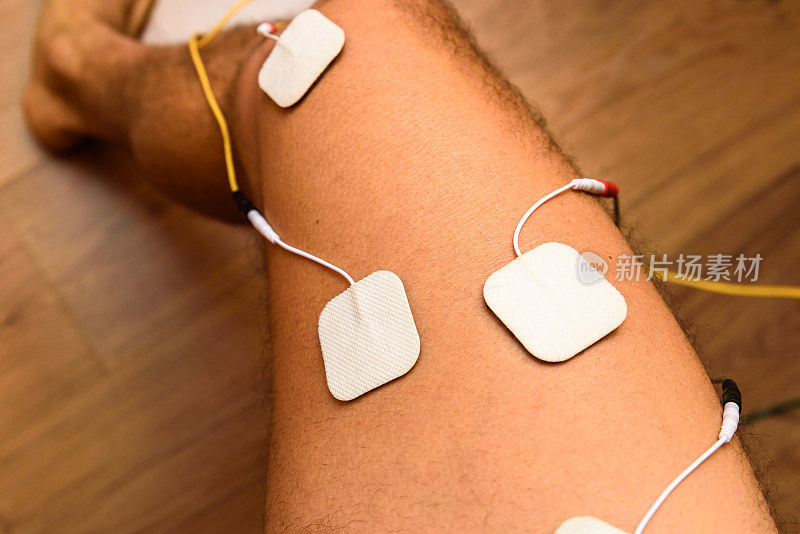一位受伤的运动员将ems电极应用到他的腿上，通过拉伸电刺激系统来恢复肌肉张力。