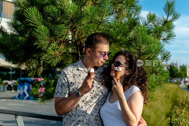 一对年轻夫妇沿着风景秀丽的河边步道享用冰淇淋