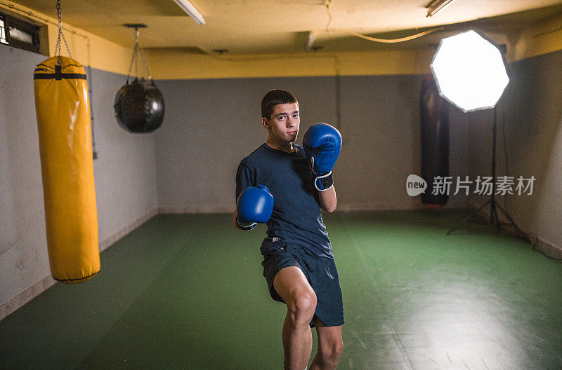 一位年轻的泰拳选手正在拳击馆练习踢腿