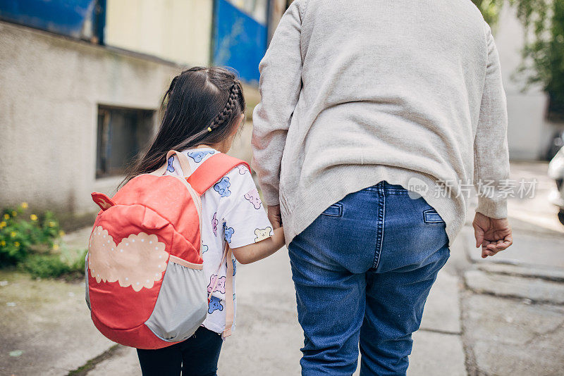 一名妇女带着学前班的孙女去上学