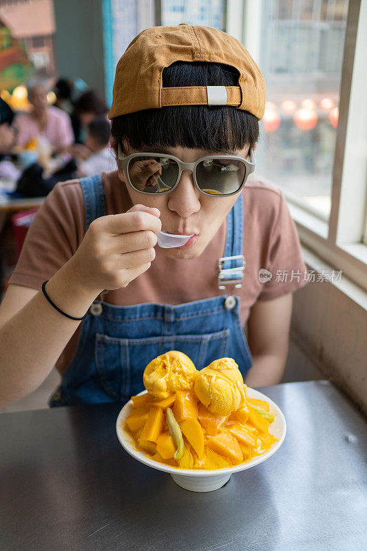 这位年轻女子在夏季旅行时吃芒果冰，清爽解渴。
