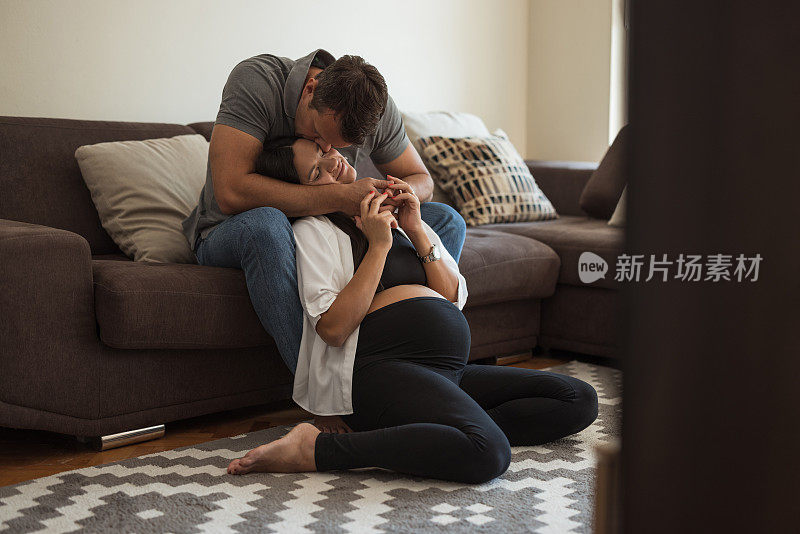 一个怀孕的女人和她的丈夫在家里享受浪漫的时刻