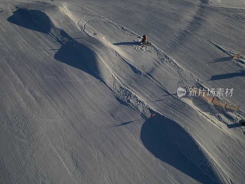 滑雪坡道上一排一排的小山孩子和大人赛跑和跳跃。造雪沿山坡分布。在温暖的天气和融化的情况下，冬天供应雪