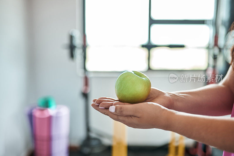 一个女人在家庭健身房拿着青苹果的侧视图