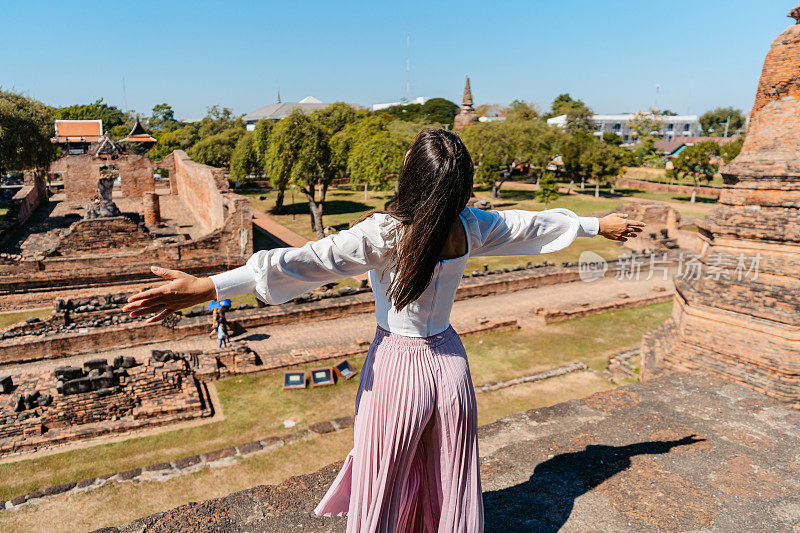 一位年轻女子在泰国大城府历史公园的Ratchaburana寺欣赏风景的后景