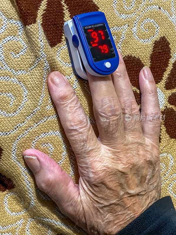 脉搏血氧计。老人的手与脉搏血氧仪的特写