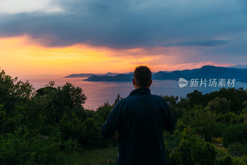 一名男子在土耳其欣赏神奇的日落，俯瞰大海和山脉