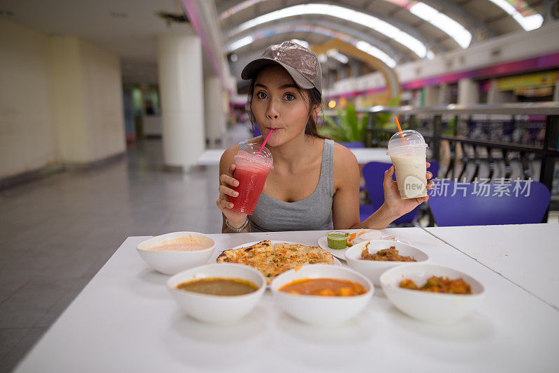 年轻美丽的亚洲女游客在餐厅享受印度美食的肖像