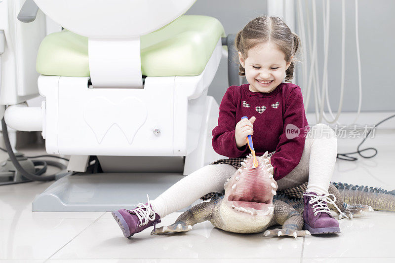 可爱的小女孩在牙科诊所拿着牙刷和玩具笑