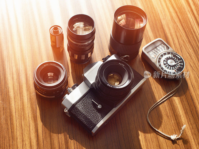 一套专业的单反相机在木桌的背景，镜头，光度计和胶卷
