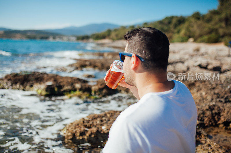 在海滩上喝啤酒的男人