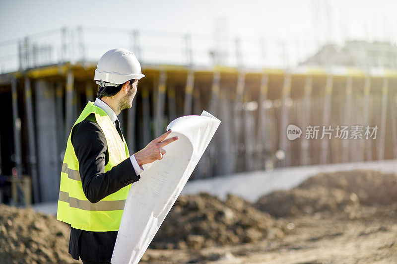 侧视图的年轻建筑工程师与项目和安全帽