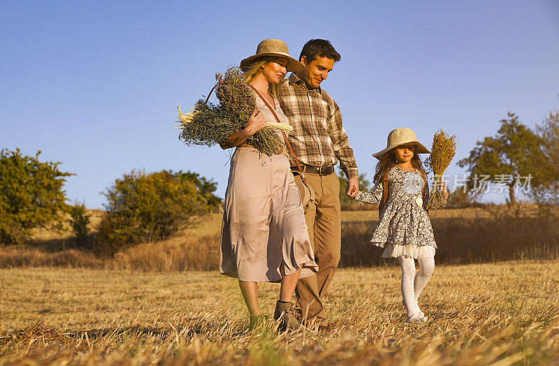 幸福的家庭:母亲，父亲，孩子，女儿对自然的秋天日落。秋日一家人在乡间散步