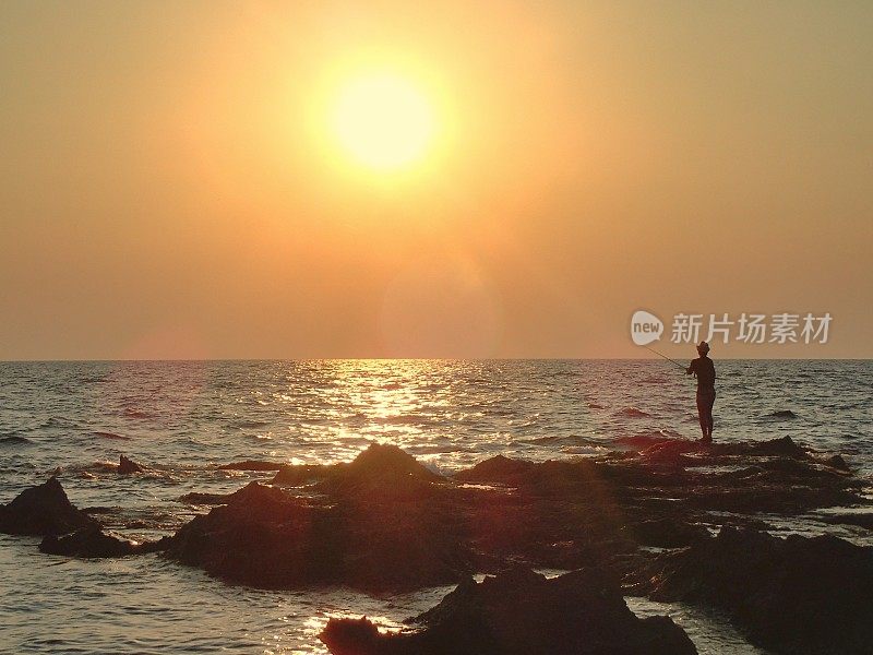 夕阳下，海面上垂钓者的剪影