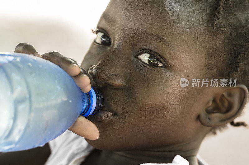 贫穷的象征:非洲黑人女孩饮用健康的淡水