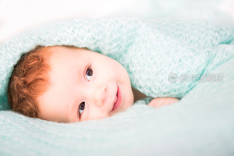 毯子下微笑的婴儿