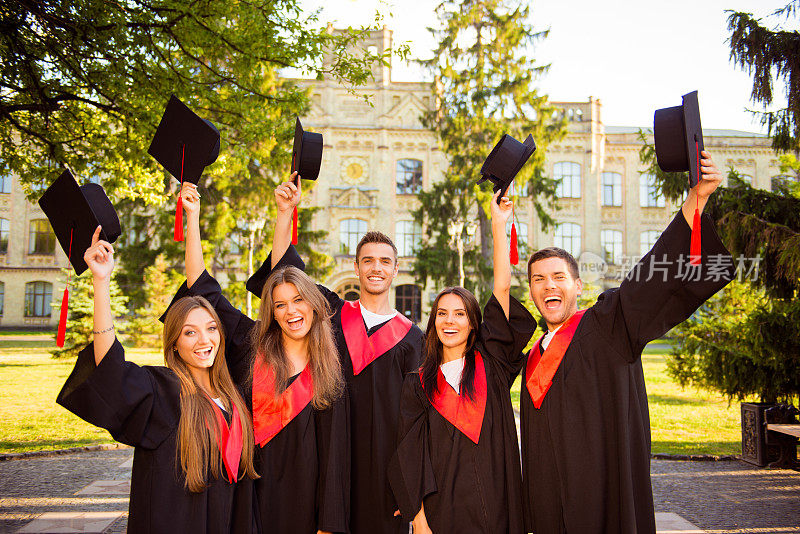 成功快乐的五名毕业生穿着长袍一起举起学位帽
