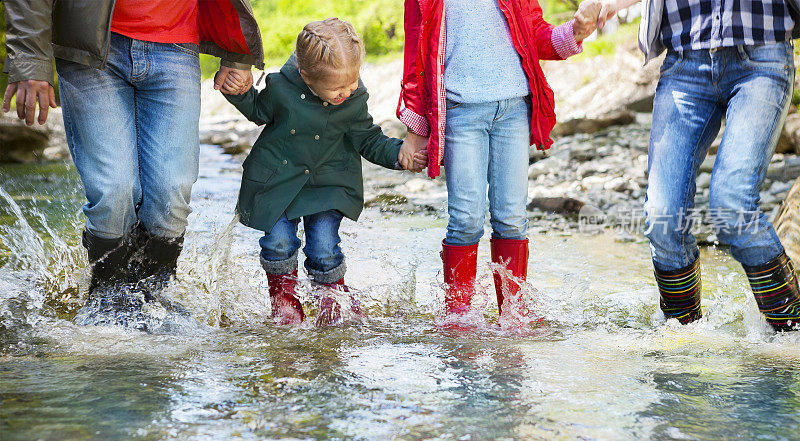 幸福的一家人穿着雨靴跳进山里的小河里