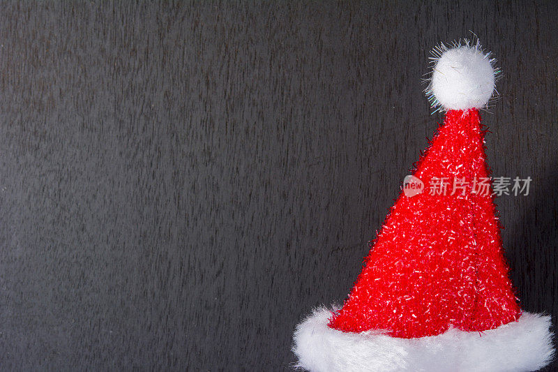 圣诞老人的红帽子放在黑色的木头上