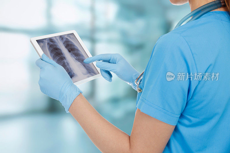 年轻外科医生在平板电脑上分析x射线的后视图