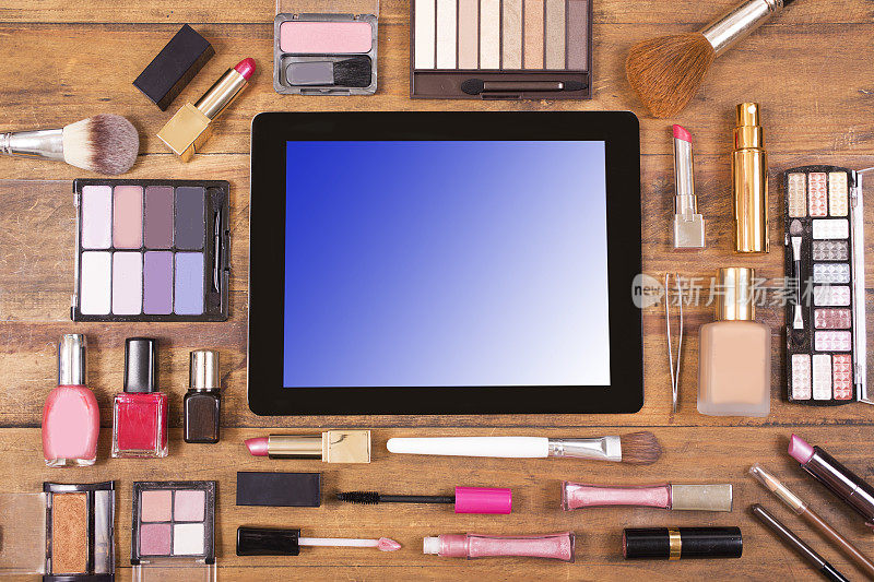 数码平板电脑周围环绕着各种化妆品。梳妆台。knol。