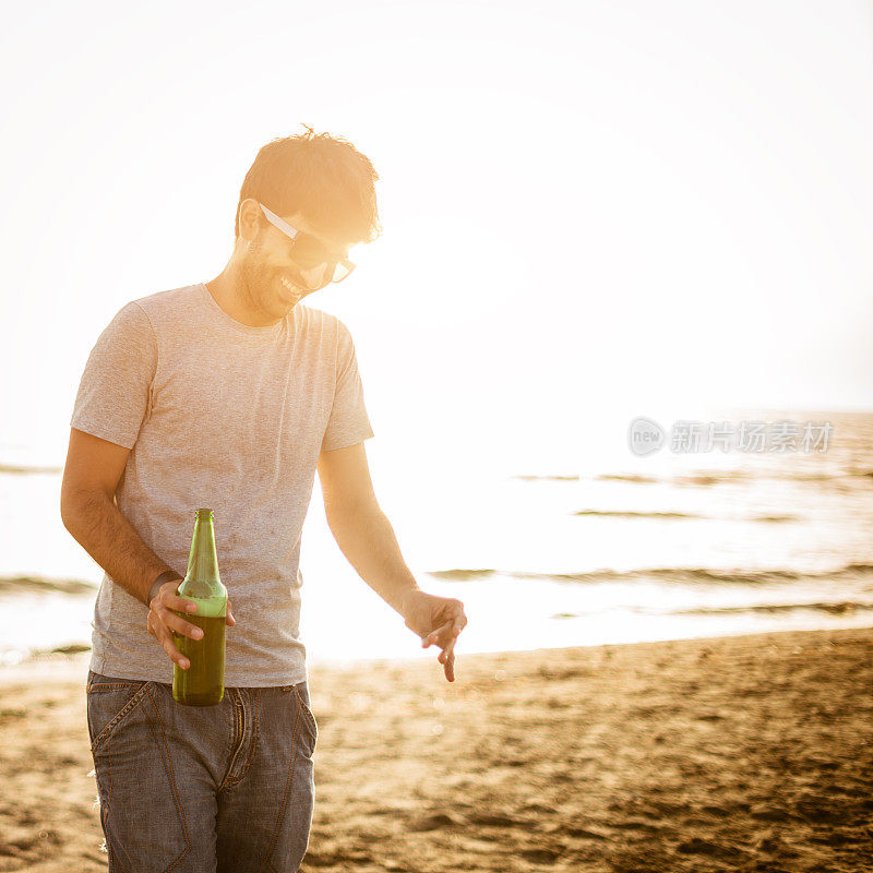 夏日沙滩上，快乐的男人拿着啤酒瓶
